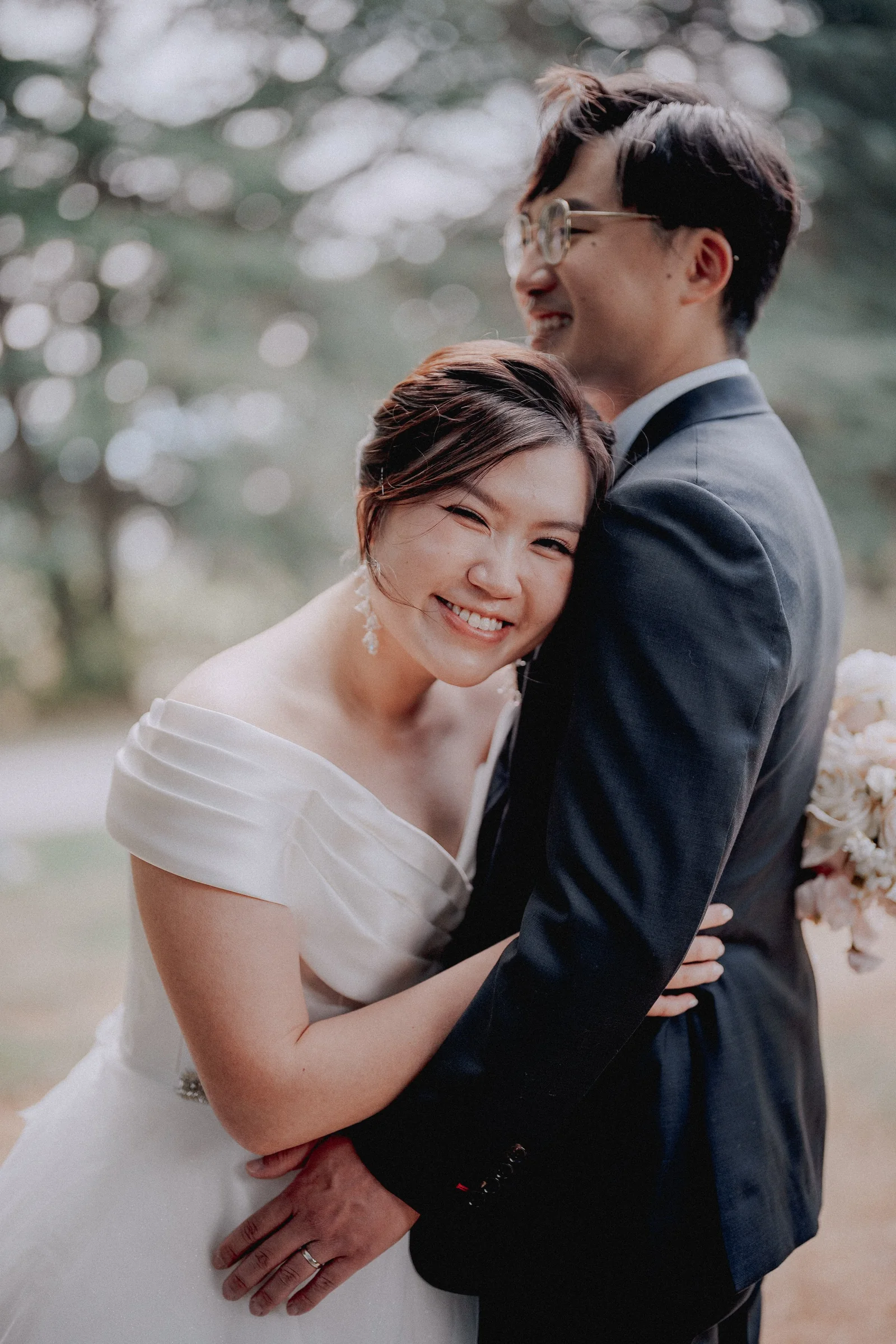 Close-up of bride hugging groom, eyes closed, genuine emotion.