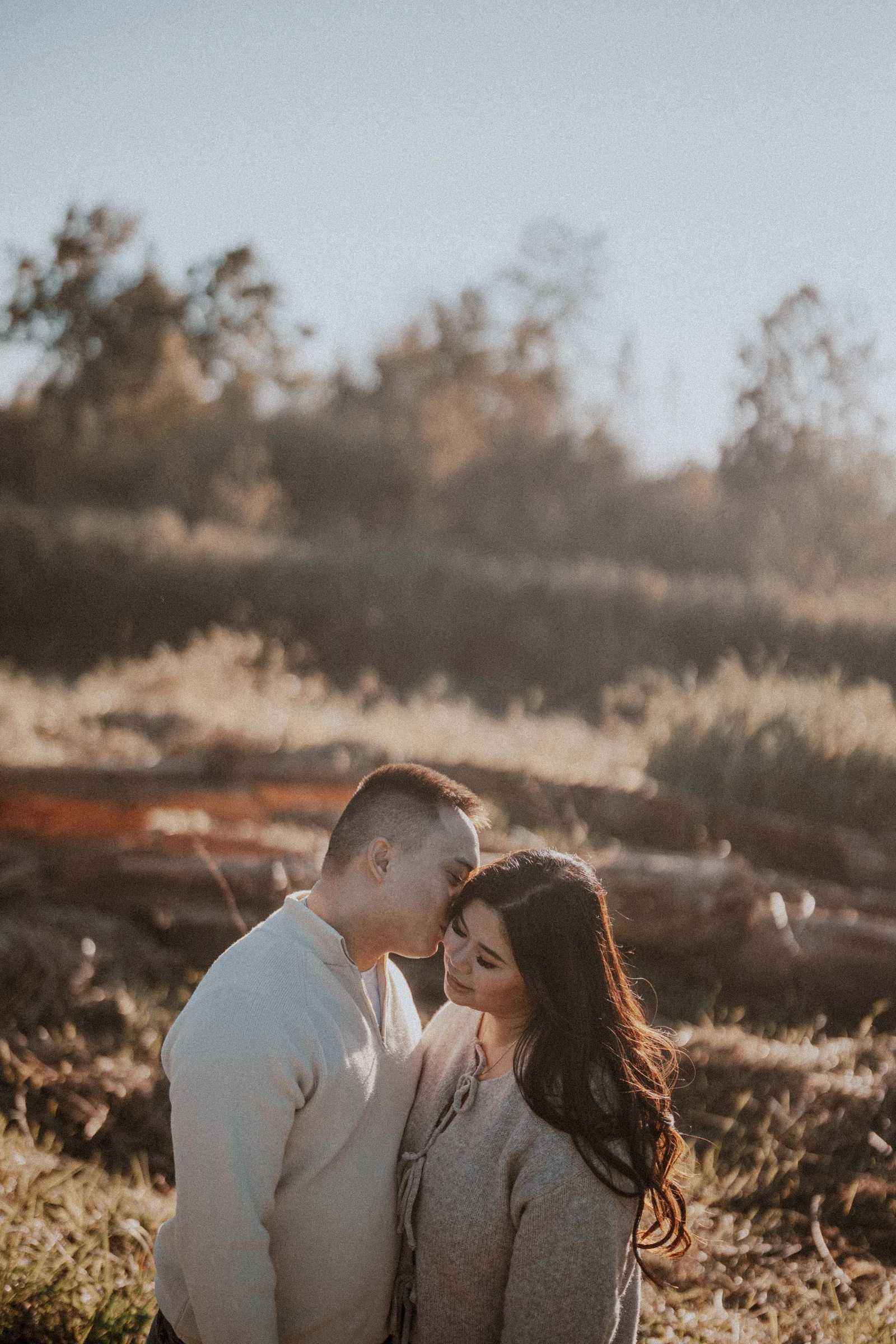 Groom kissing bride's forehead, intimate and tender moment, Pitt Lake golden hour.