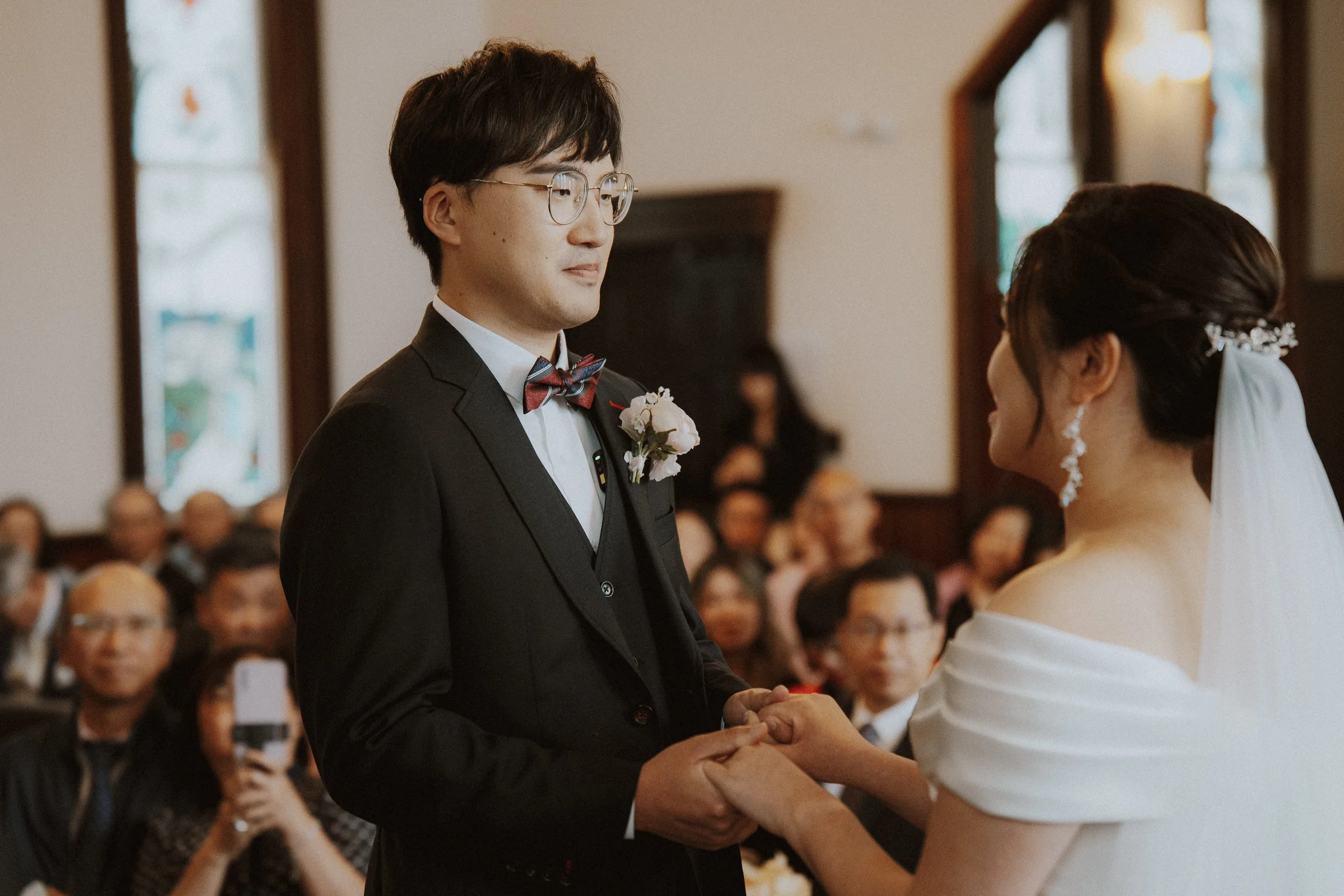 Groom holding the bride's hands during their Minoru Chapel vows.