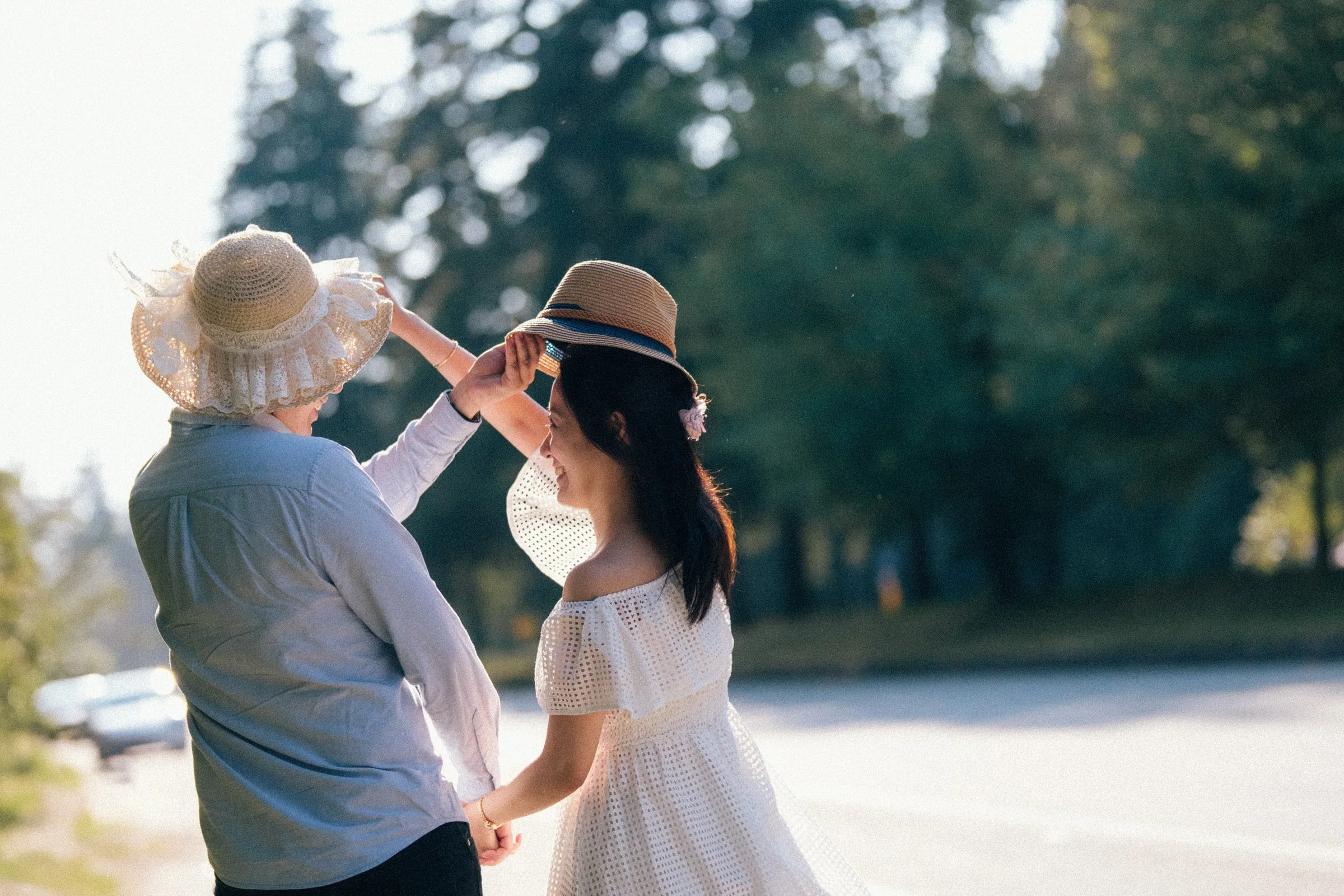 Couple adjusting straw hats, playful and candid moment, Vancouver forest.