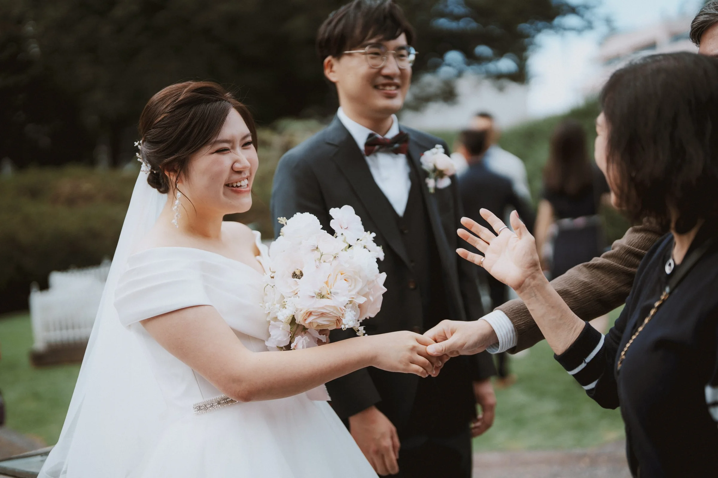 Bride greeting a guest while the groom smiles beside her.