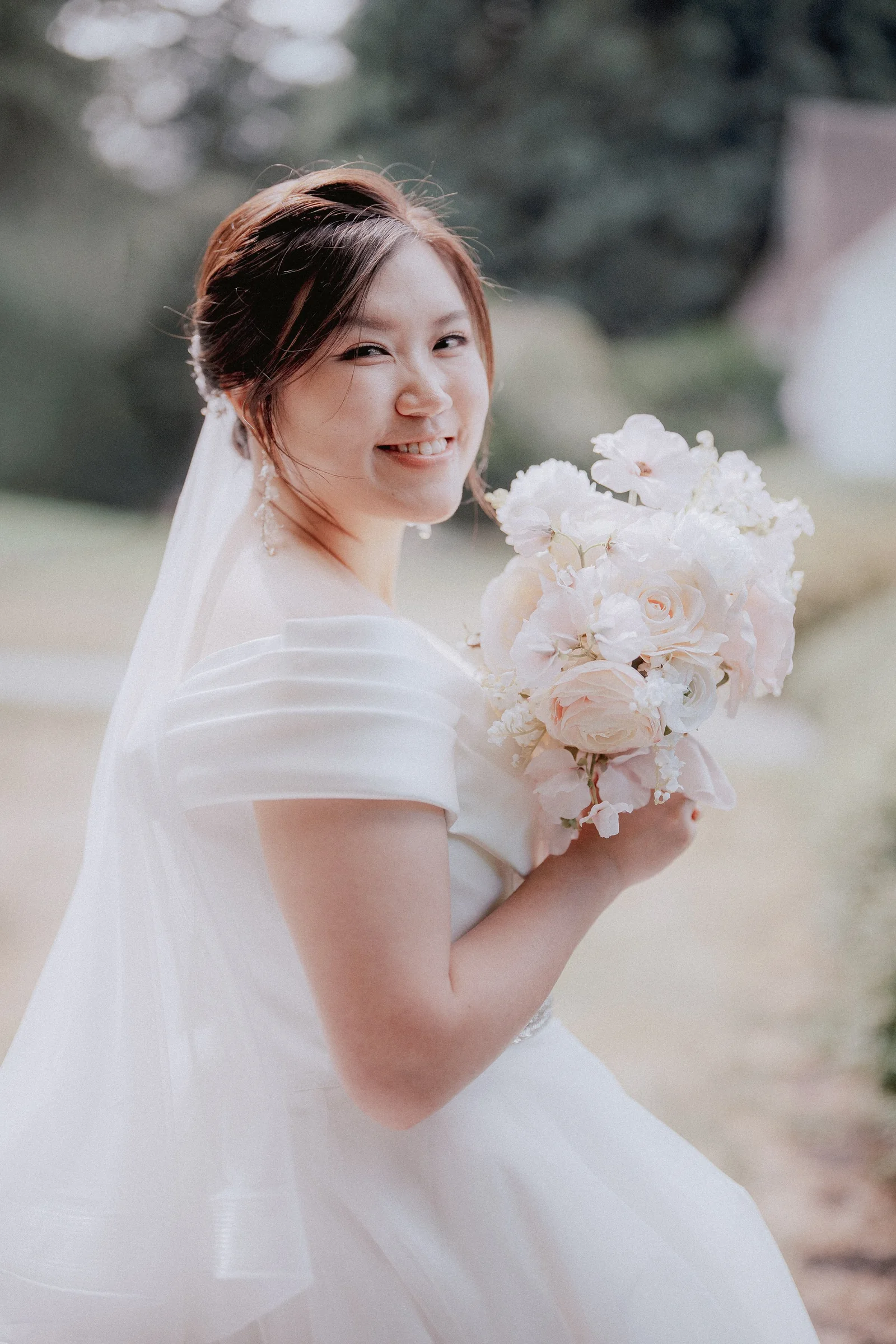 Bride smiling over her shoulder while holding her bouquet.