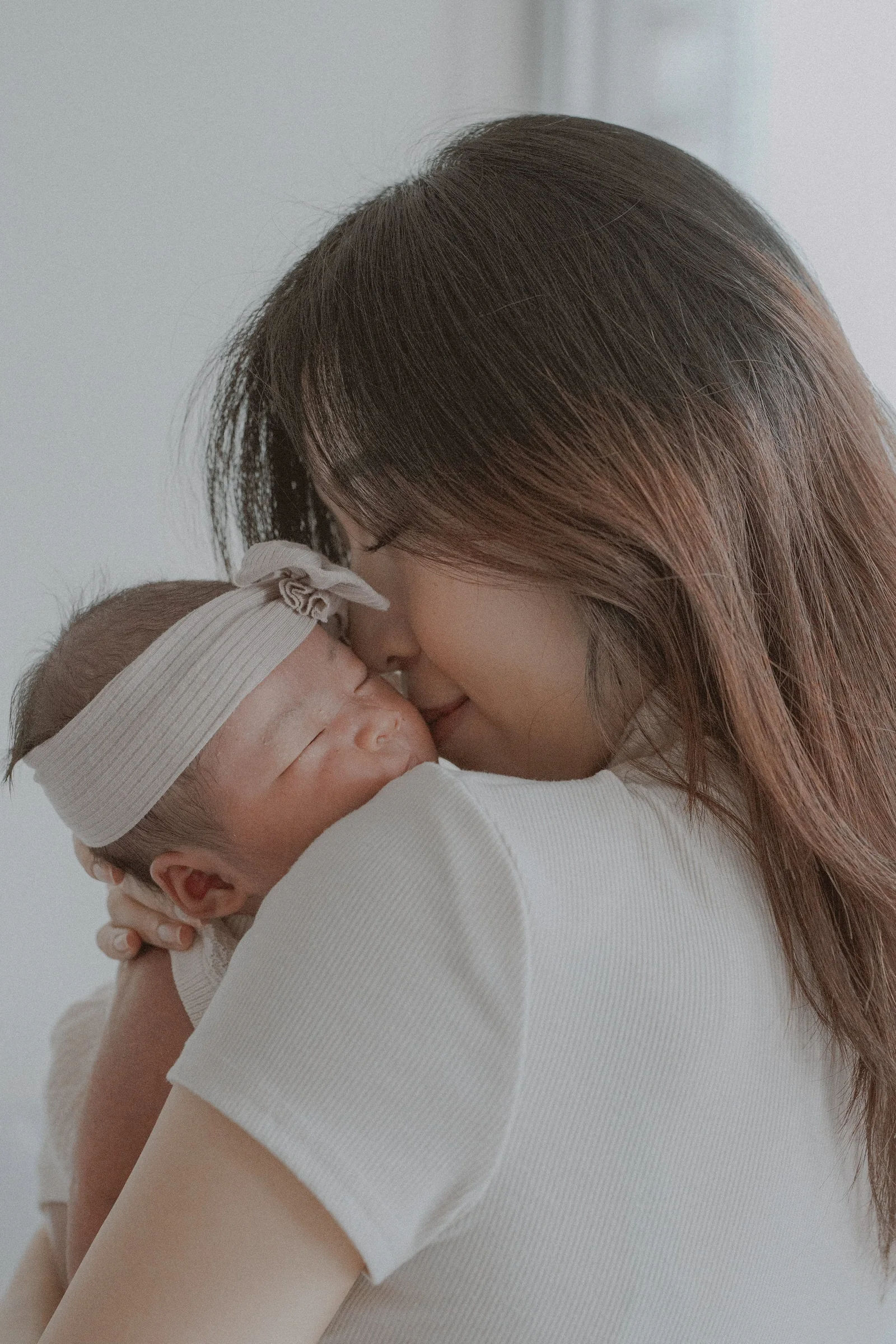 Close portrait of a parent cuddling a newborn against their chest.