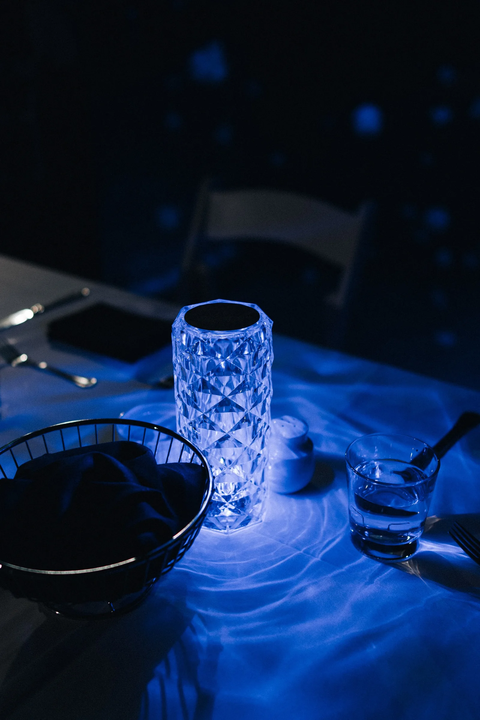 Blue-lit cut-glass candle holder and place setting at the wedding reception.