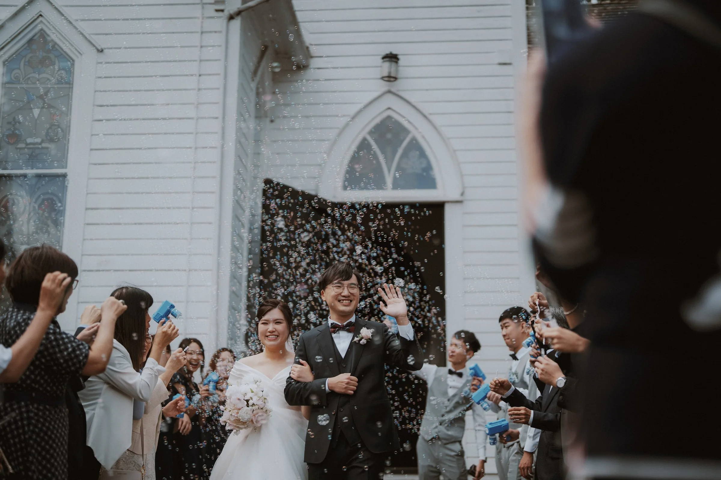 Bubbles drifting around the newlyweds outside the chapel doorway.