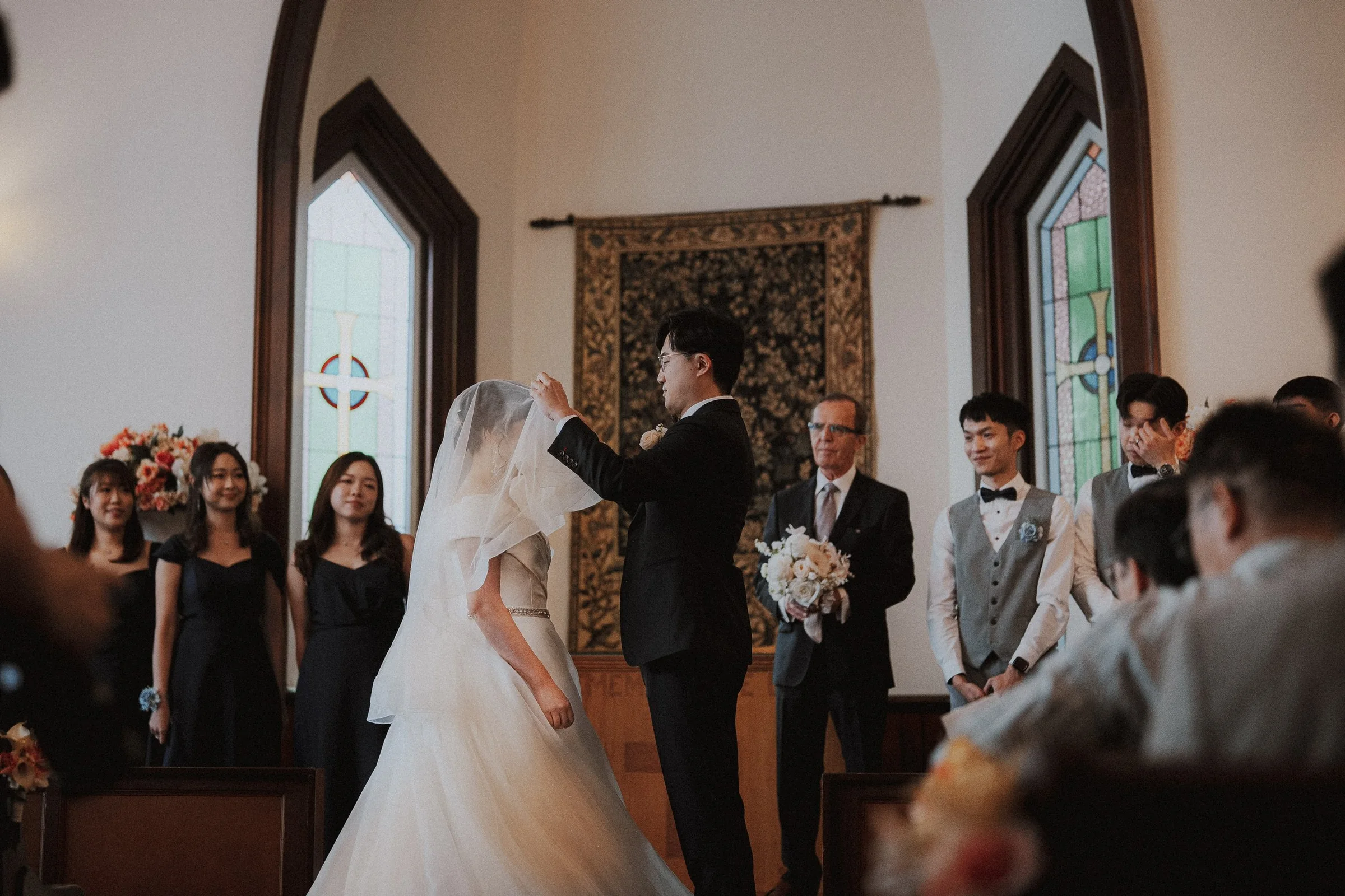Groom lifting the bride's veil before their vows.