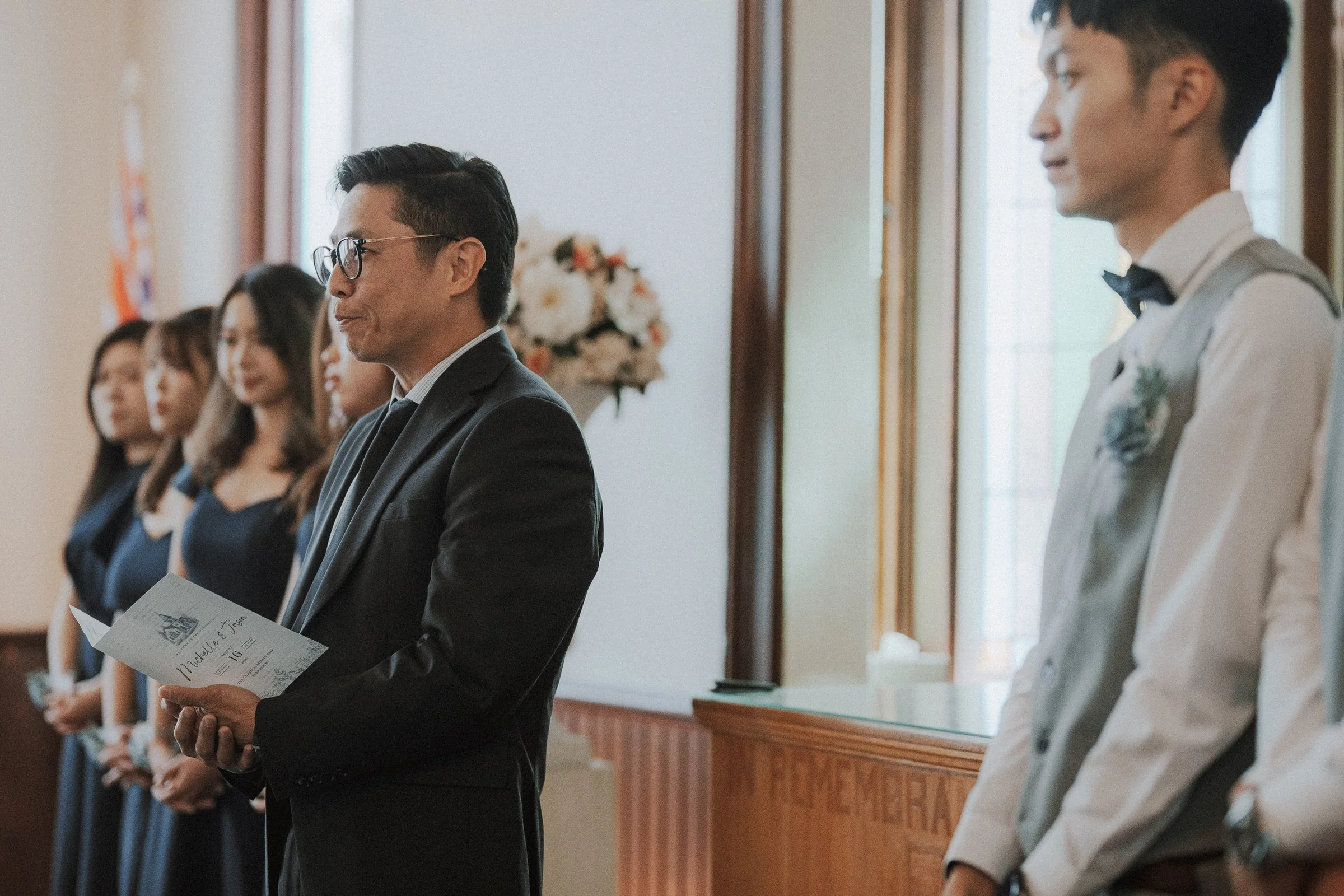 Guest reading from a card beside the wedding party inside the chapel.