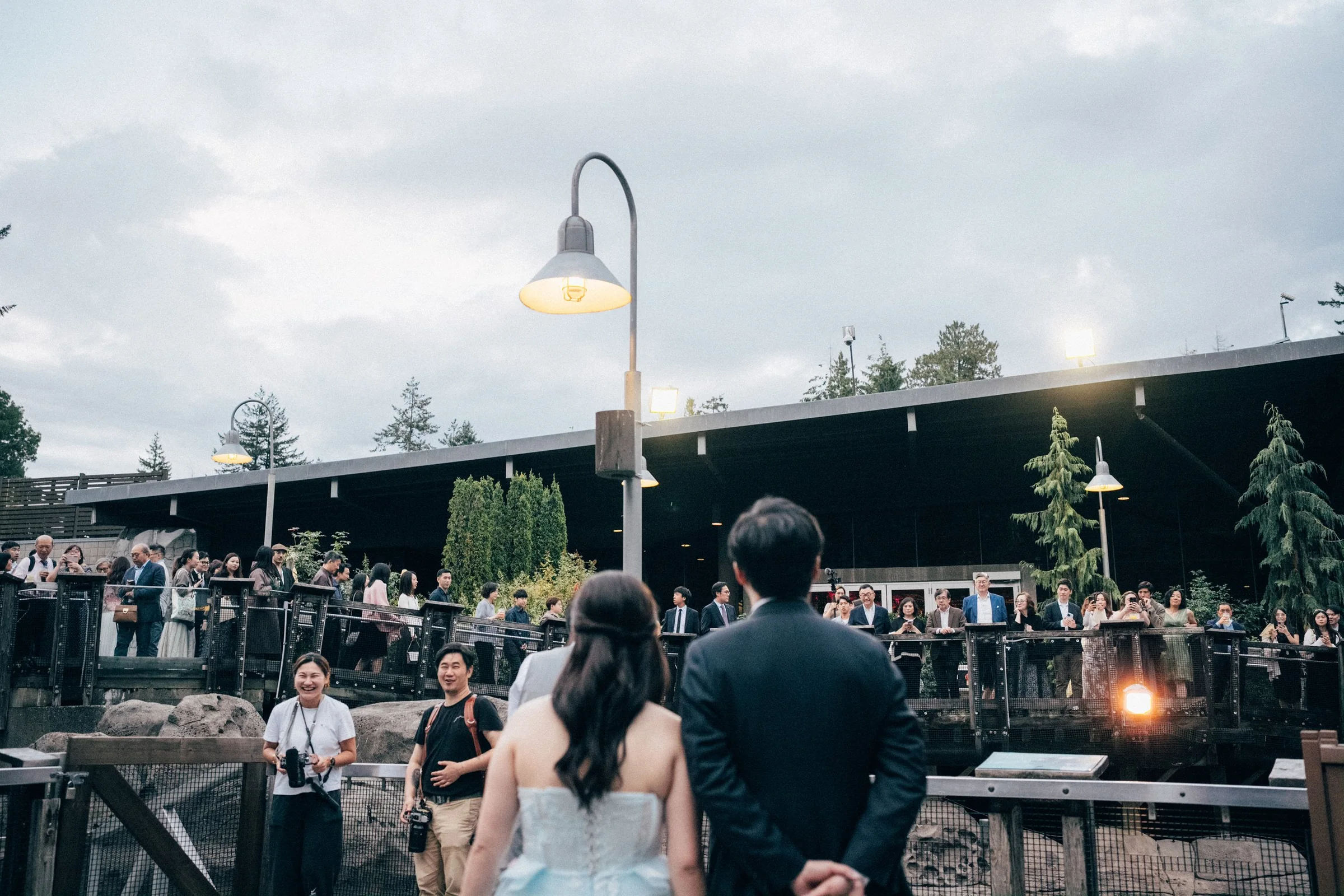 Couple approaching wedding guests gathered on the Vancouver Aquarium terrace.