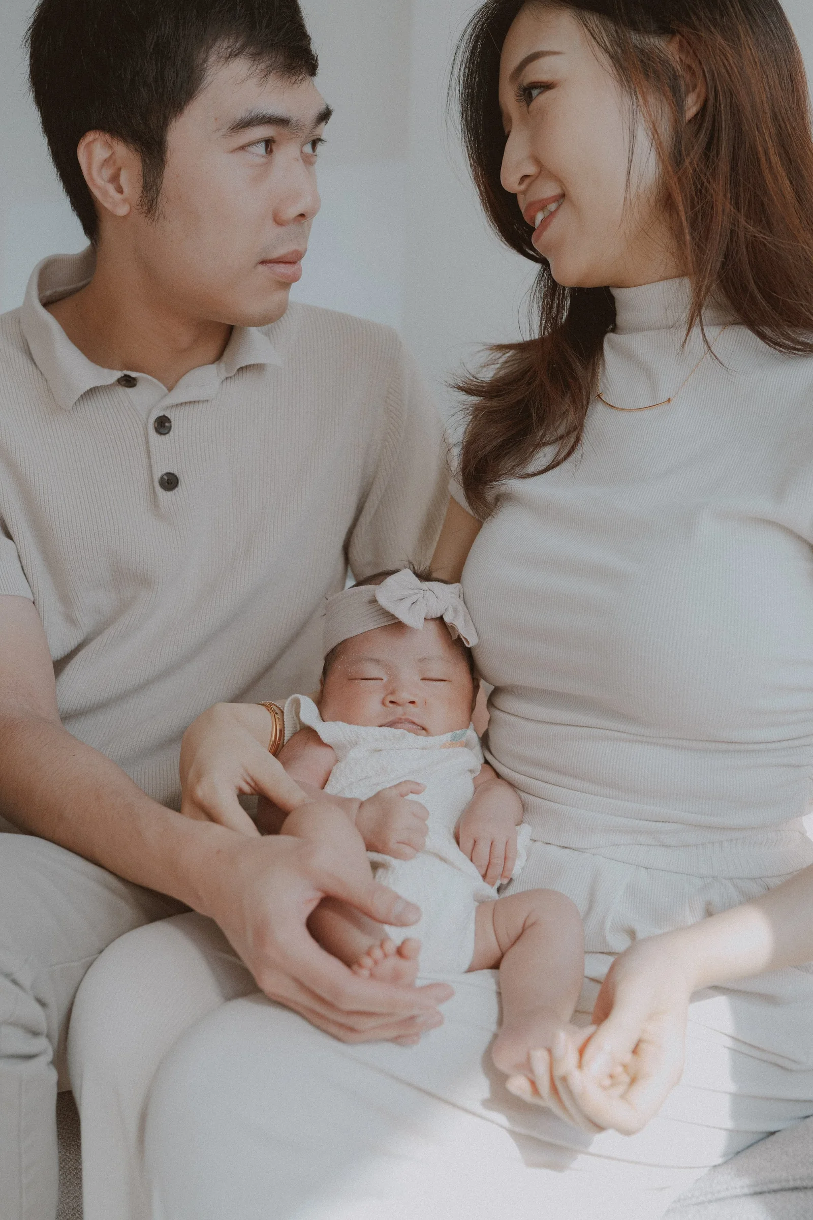 Parents looking at each other while holding their newborn together.