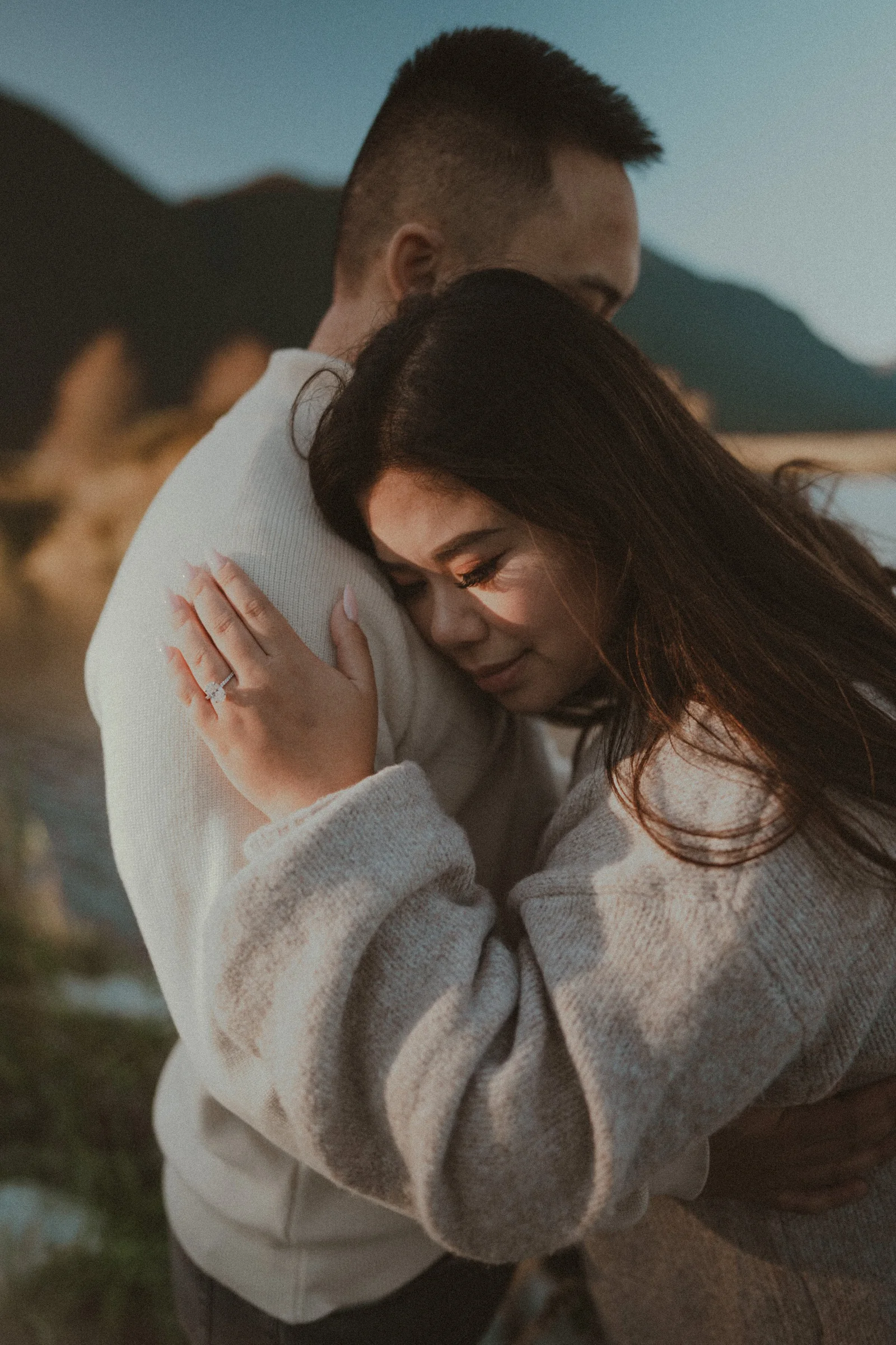 Bride hugging groom , showing engagement ring, soft light portrait.