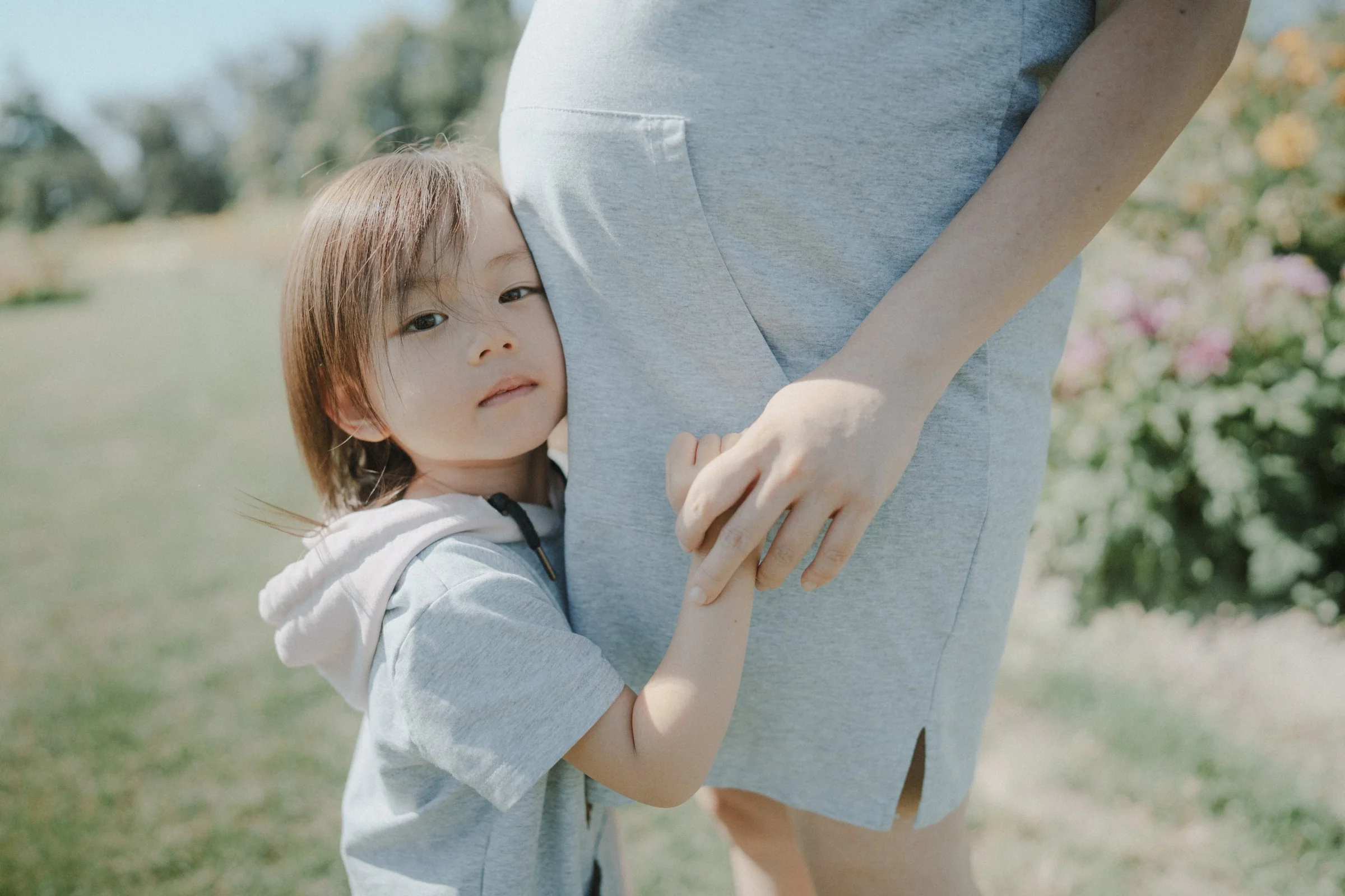 Child hugging pregnant belly in sunlit garden at Richmond Country Farms